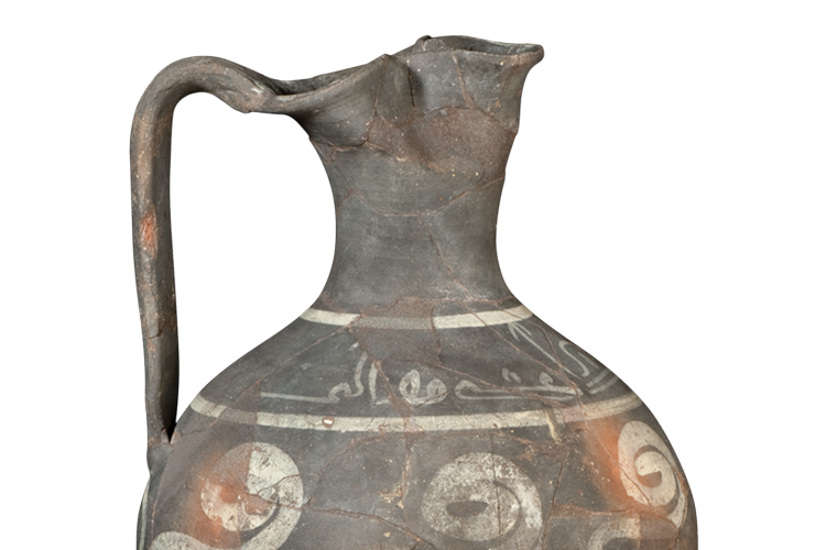 A tall ceramic vessel reconstructed from fragments, with a narrow neck, a spout, and a handle, and is painted with abstract bands and calligraphy.