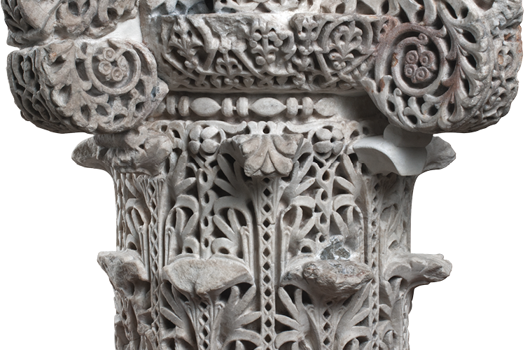 The topmost part of a stone column carved with S-scrolls, stylized acanthus leaves, and interstitial geometric designs.