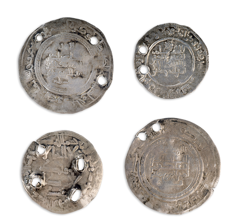 Four flat silver discs with Islamic calligraphy, some effaced, in relief. Each is perforated with two, three, or four holes.