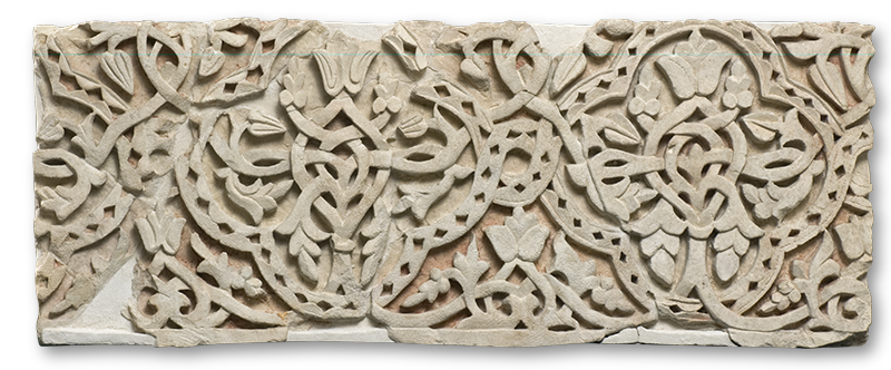 A rectangular stone plaque carved in relief with interlacing vegetal designs.