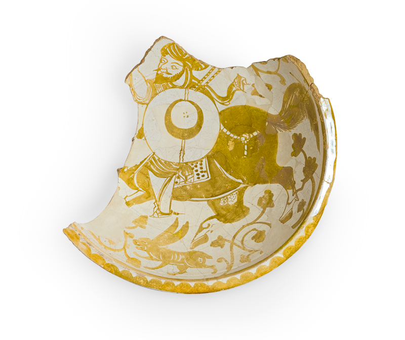 The ceramic fragment of a dish painted at the center to depict a man carrying a shield and riding a horse, along with a rabbit and vegetal designs.