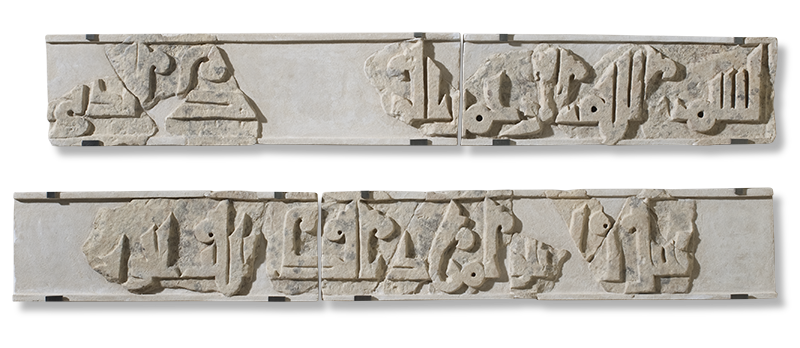 Fragments of stone with Islamic calligraphy carved in relief and arranged in two long rows.