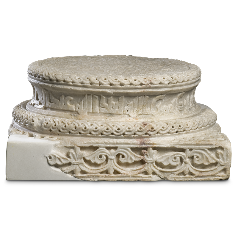 Stone carved as a round platform on a rectangular base and decorated with carved interlacing designs.