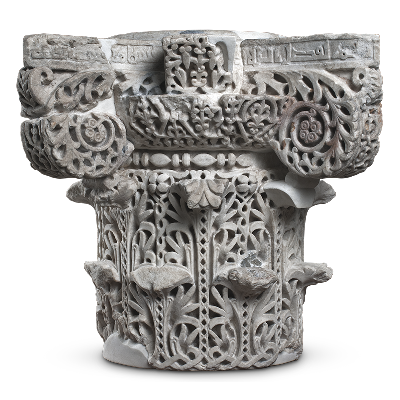 The topmost part of a stone column carved with S-scrolls, stylized acanthus leaves, and interstitial geometric designs.