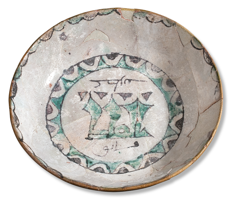 A deep round dish decorated at the center with a ring of geometric forms enclosing calligraphy. Scalloped decoration is painted around the rim.