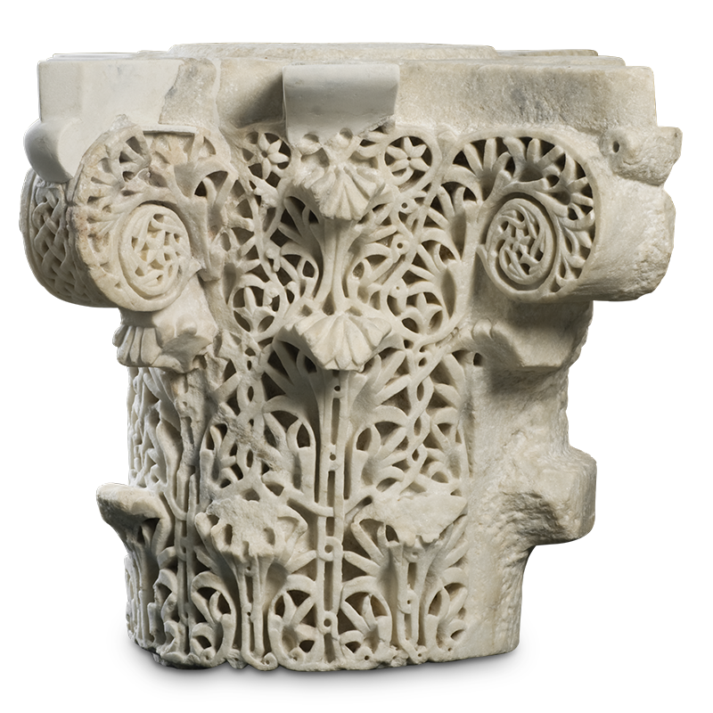 The topmost part of a stone column carved with S-scrolls, stylized acanthus leaves, and interlacing designs.