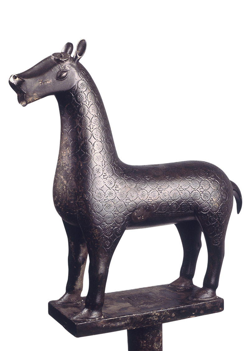 A bronze sculpture in the round of a four-legged animal decorated with incised circles, each enclosing a stylized leaf.